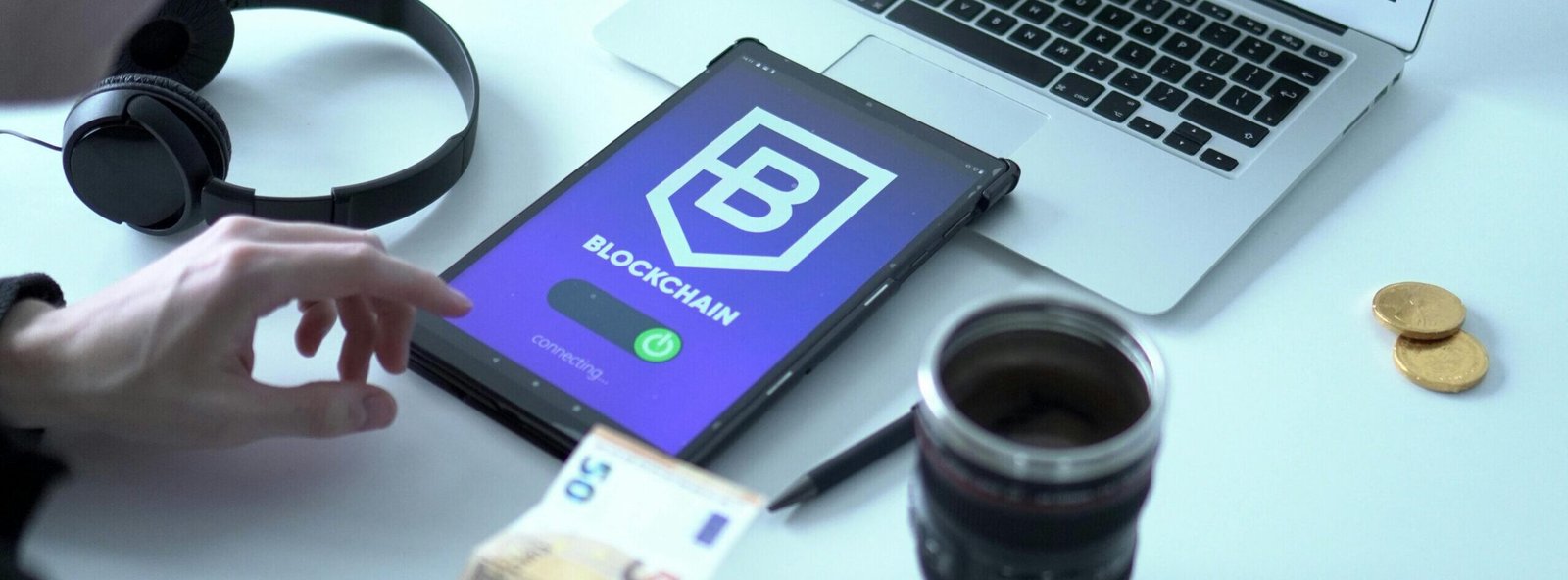Close-up of digital currency transaction using blockchain technology on tablet with laptop and euro bills.